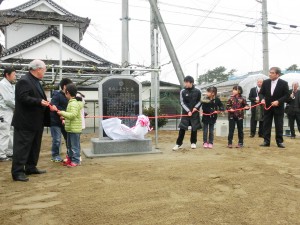 除幕式を行う児童と石碑建立委員会メンバー