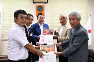 モモを東松島市へ託す生産者(右)