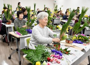 説明を聞きながら真剣に花を生ける参加者