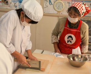 女性部が見守る中、慎重にそばを切る生徒